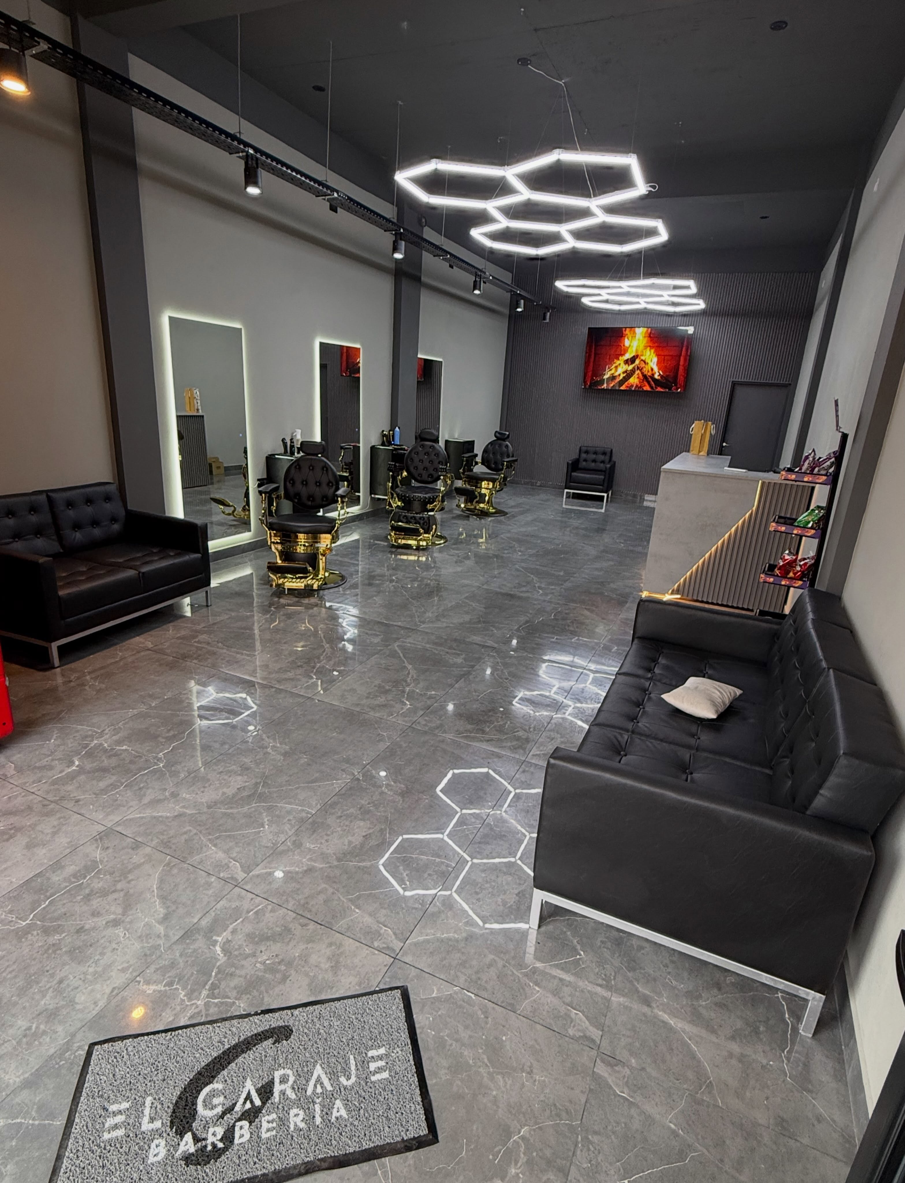 Interior de El Garaje: sillones negros con bases doradas, espejos y luces hexagonales